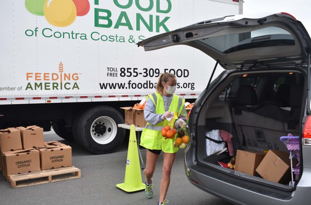 Volunteer delivers free food to a community member's car.