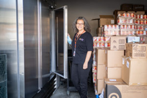 Chelo stand in front of two freezers. These freezers were purchased through the Food Bank's agency enhancement grants.