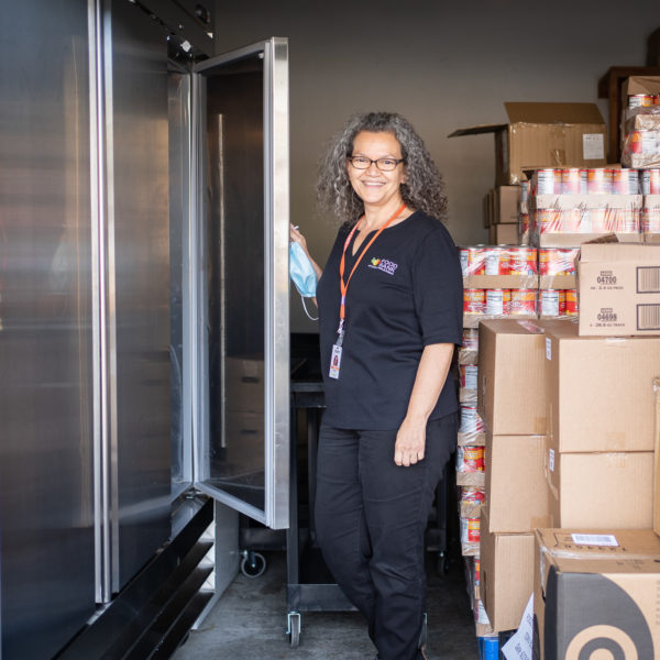 Chelo stand in front of two freezers. These freezers were purchased through the Food Bank's agency enhancement grants.