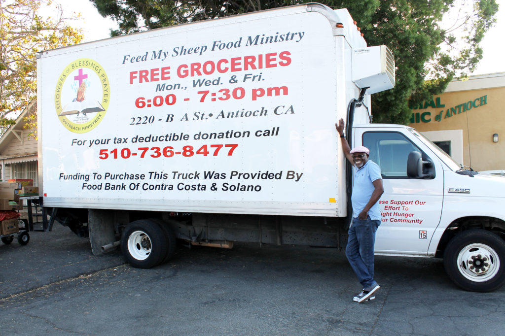 Pastor Sylva stands next to Showers of Blessings' refrigerated truck.