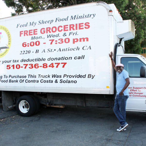 Pastor Sylva stands next to Showers of Blessings' refrigerated truck.