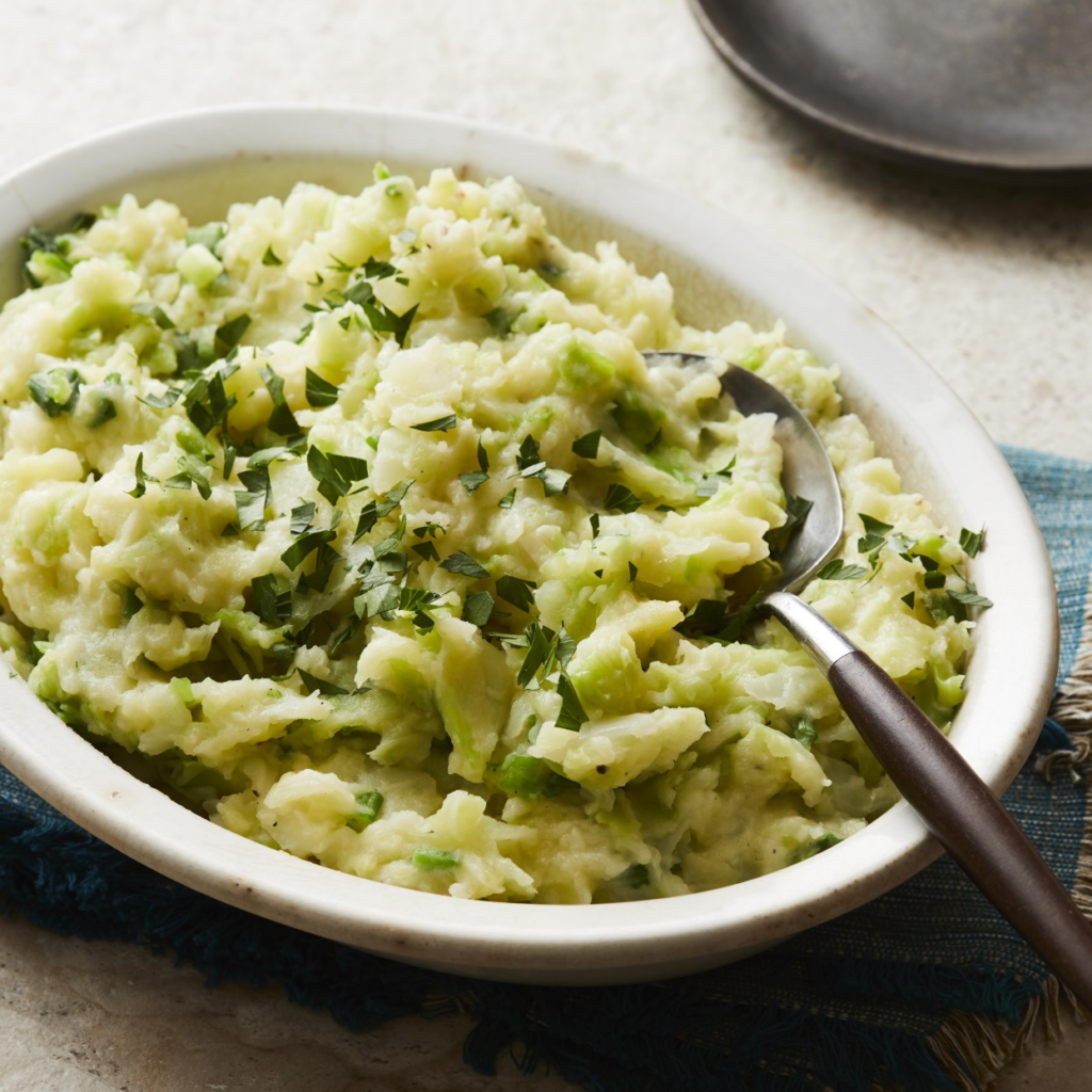 A white bowl filled with mashed potatoes and greens mixed together.