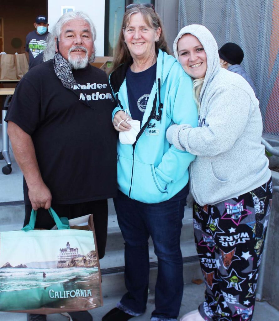 Familia sonriendo con bolsa de distribución de alimentos