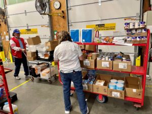Volunteers look through boxes of food in a grocery store stock room.