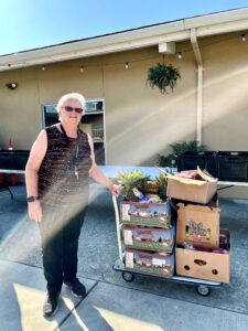 A volunteer poses with a cart of rescued food.