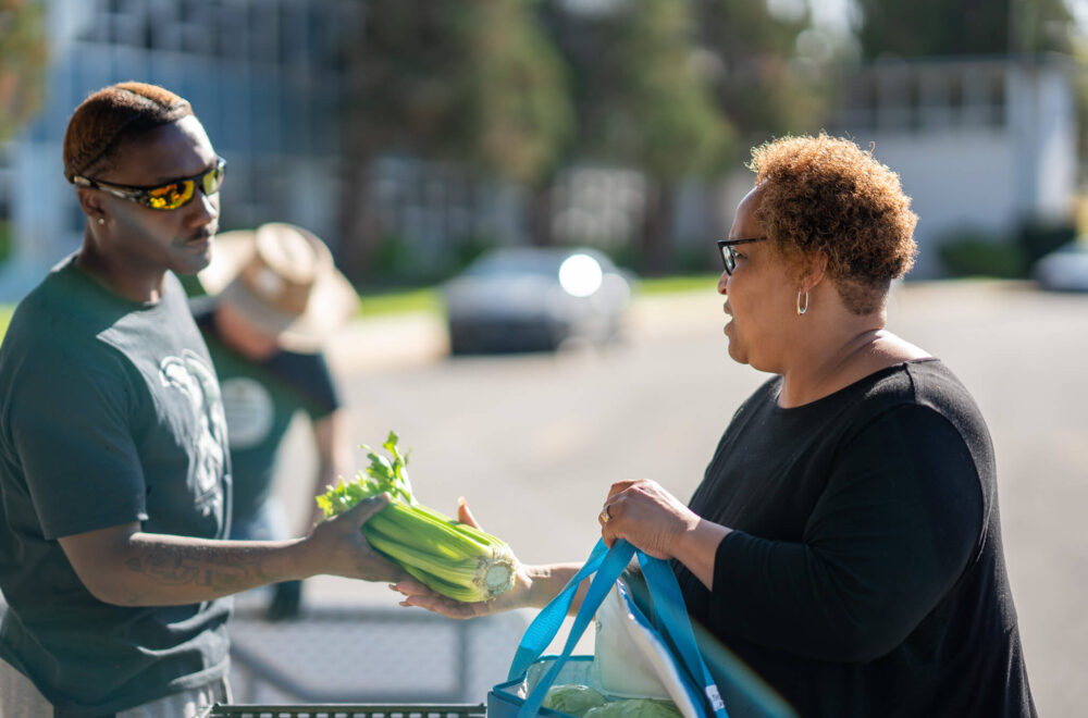 A volunteer hands out free food to a community member.