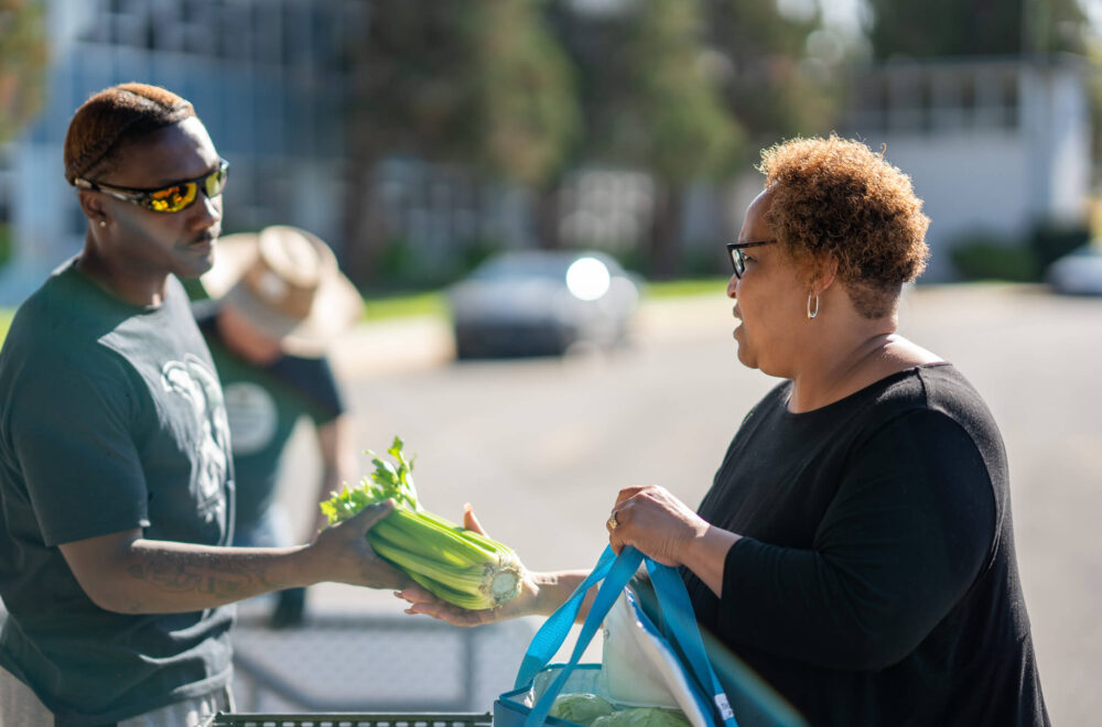 Un voluntario reparte comida gratis a un miembro de la comunidad.