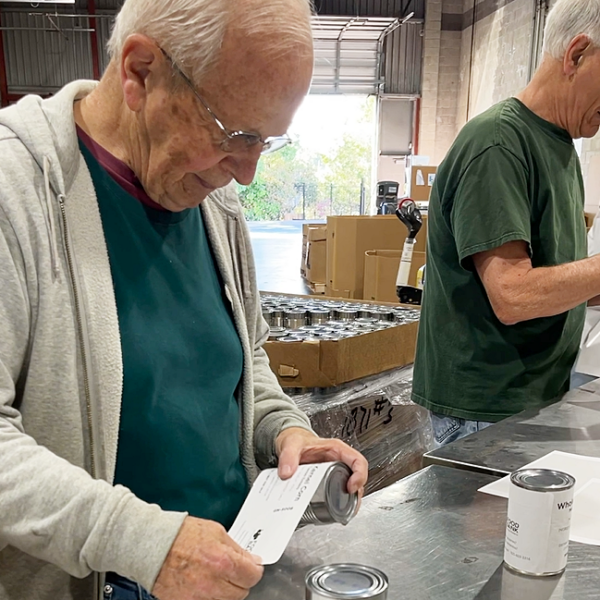 Volunteers label cans at our warehouse