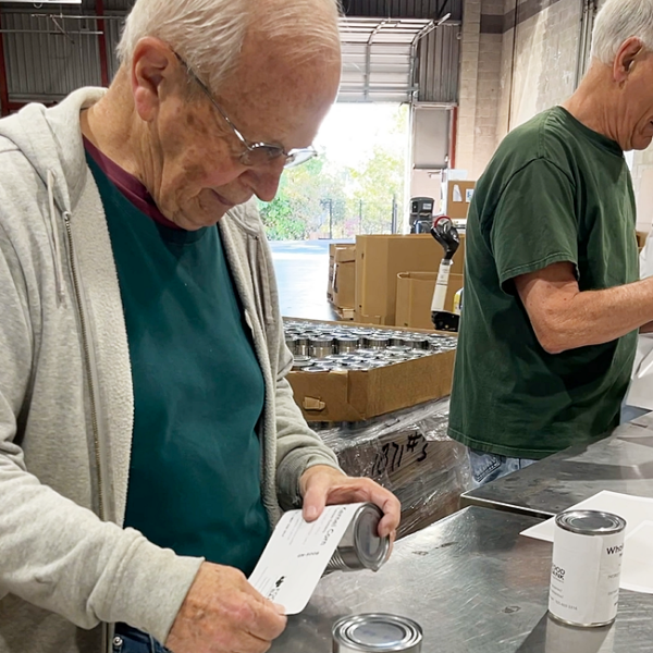 Voluntarios etiquetan latas en nuestro almacén