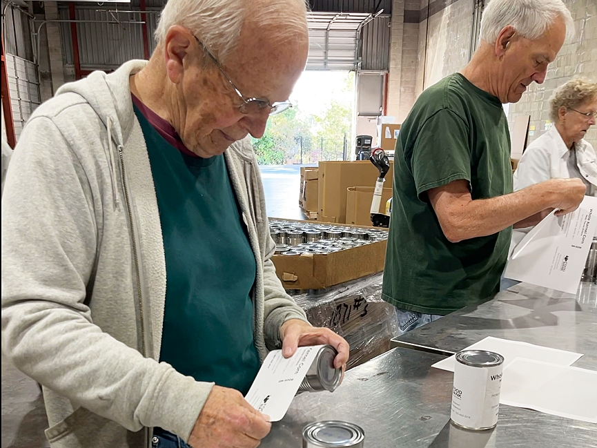Volunteers label cans at our warehouse