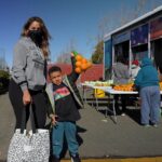 Madre e hijo reciben productos frescos en la distribución del Banco de Alimentos.