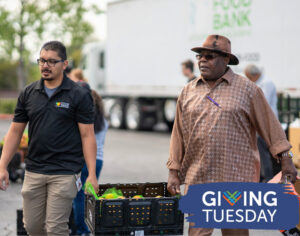 Two men carry a box of produce together