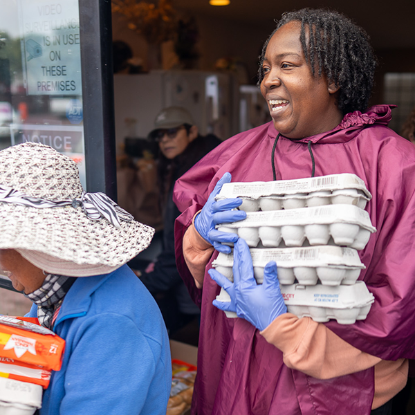 Two volunteers hand out food at a Food Bank partner agency.
