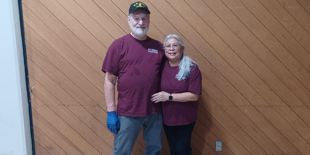 Two volunteers in matching shirts pose for a photo.
