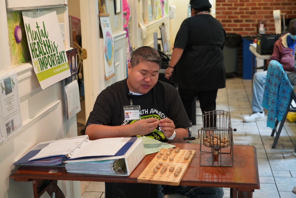 A Caminar staff member reads out numbers during a bingo game.
