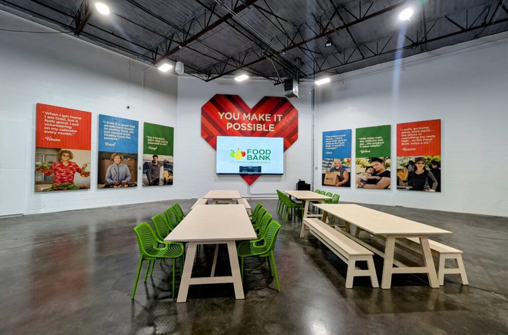 Chairs and tables in a newly painted warehouse with art on walls.