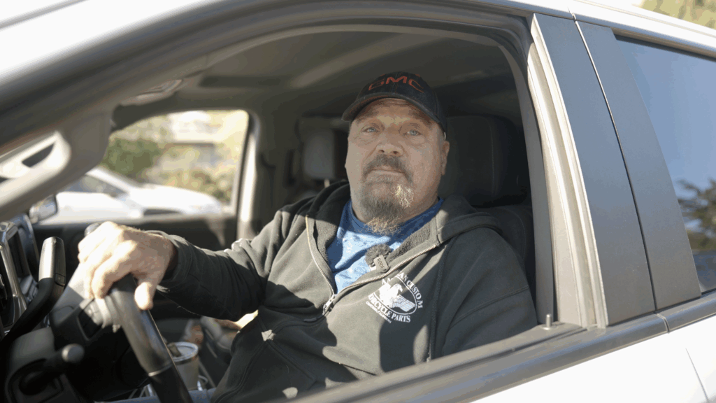 A man sits in the cab of a pickup truck.