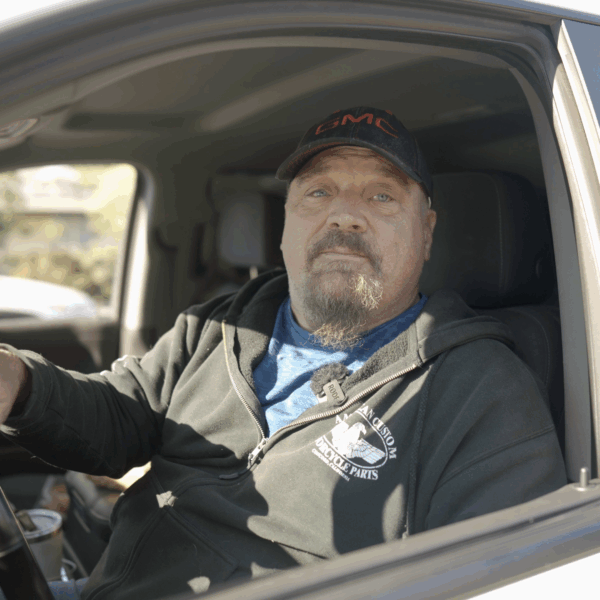 A man sits in the cab of a pickup truck.