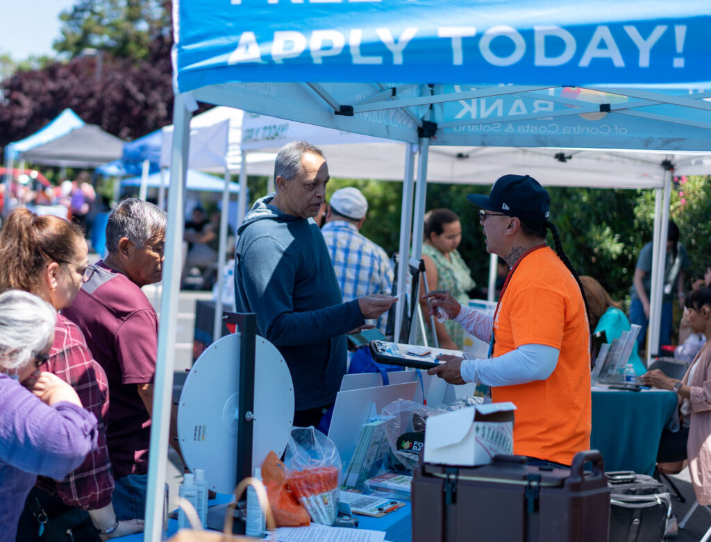 A CalFesh team member talks to the public at a resource fair.