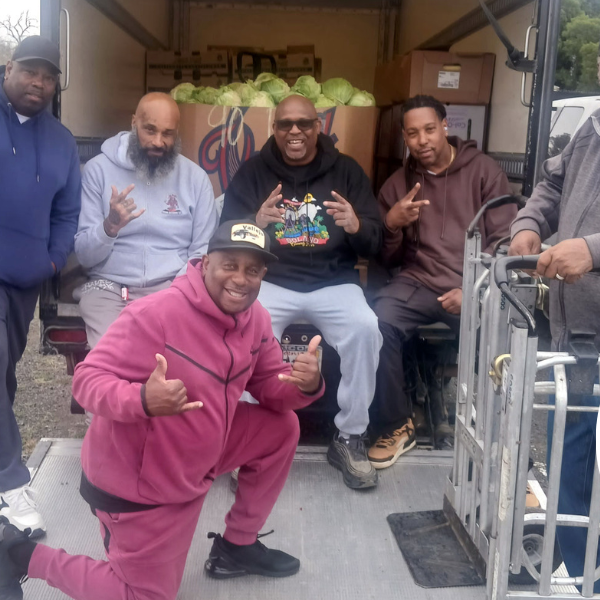 Boys and Girls Empowerment Group staff pose in front of their new box truck filled with cabbage.
