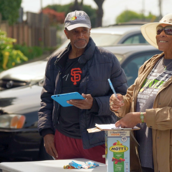 Two Food Bank volunteers check in neighbors at a distribution.