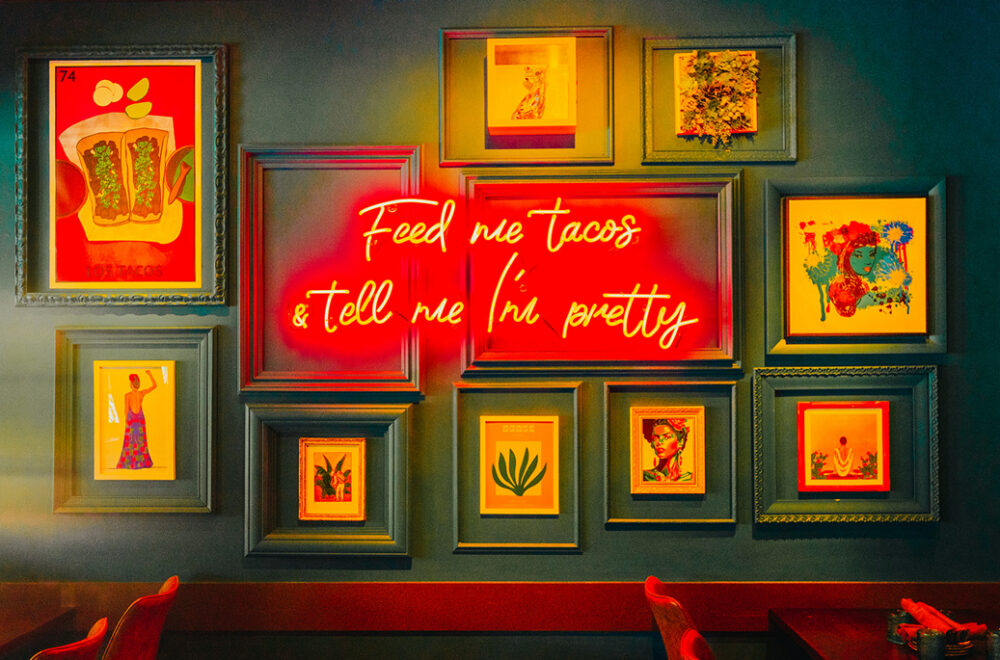Sign on wall of restaurant says "Feed me tacos & tell me I'm pretty"
