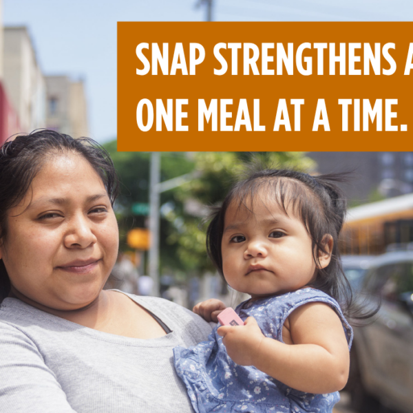 A mother holds her young child and looks directly at the camera. SNAP strengthens America one meal at a time.